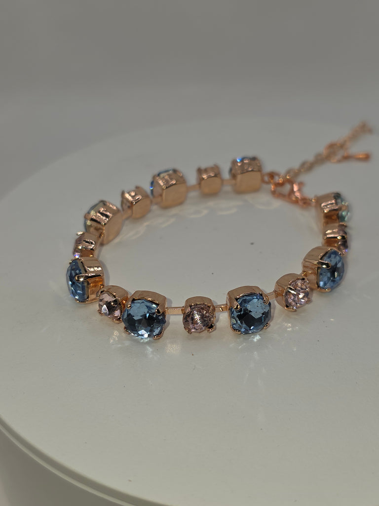 Bracelet with rose gold and blue gemstones on a white background